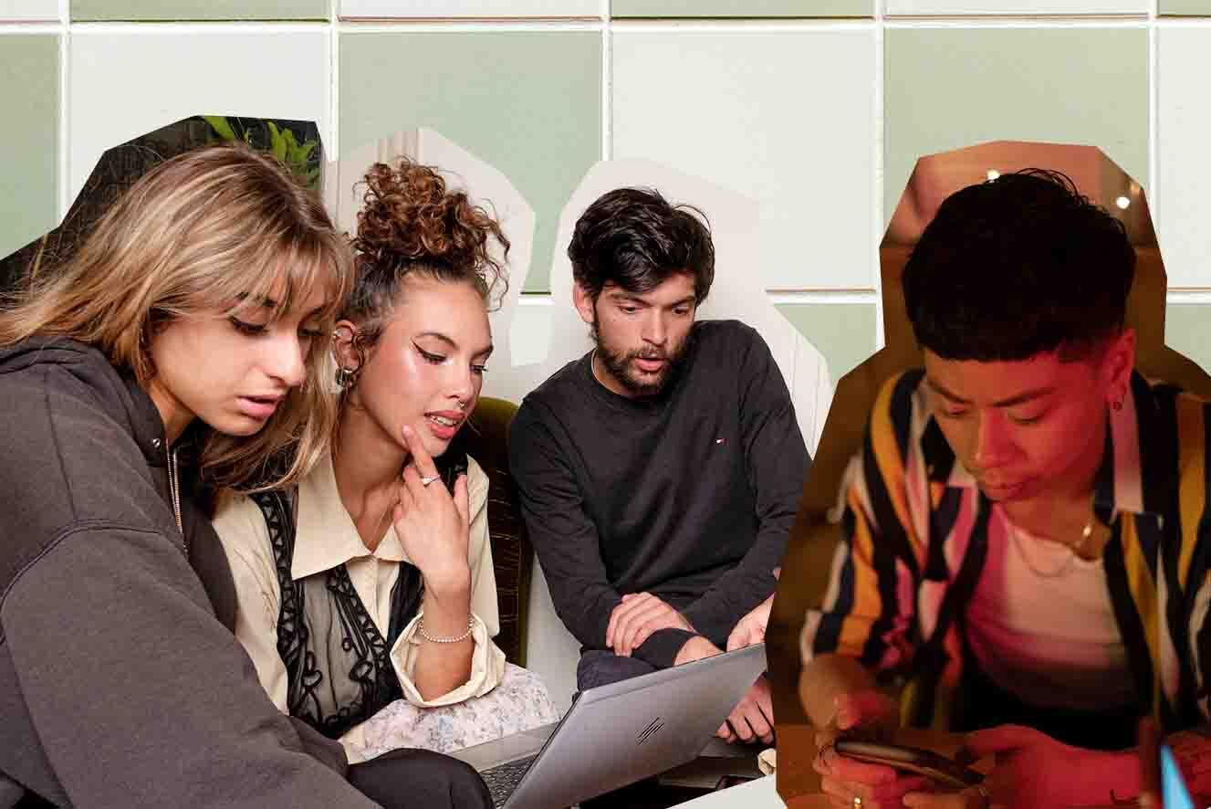 Four individuals are engaged in a focused group discussion around a table, with one person using a laptop and another looking at a mobile phone. Background is green and white tiles.