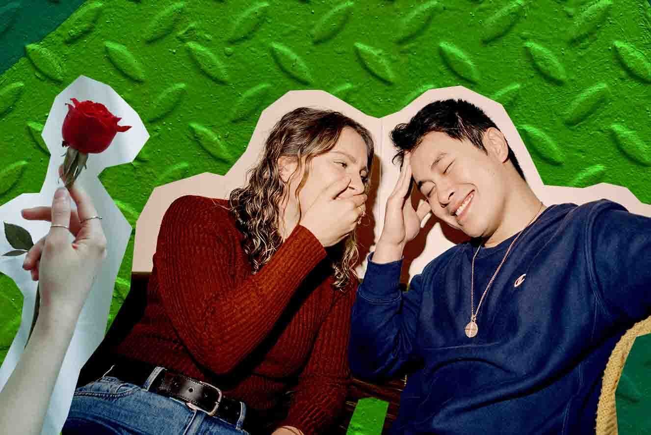 Against a bright green background a young women wearing a red jumper whispers into a young man wearing blues ear, both are smiling. To their left a hand holds a red rose