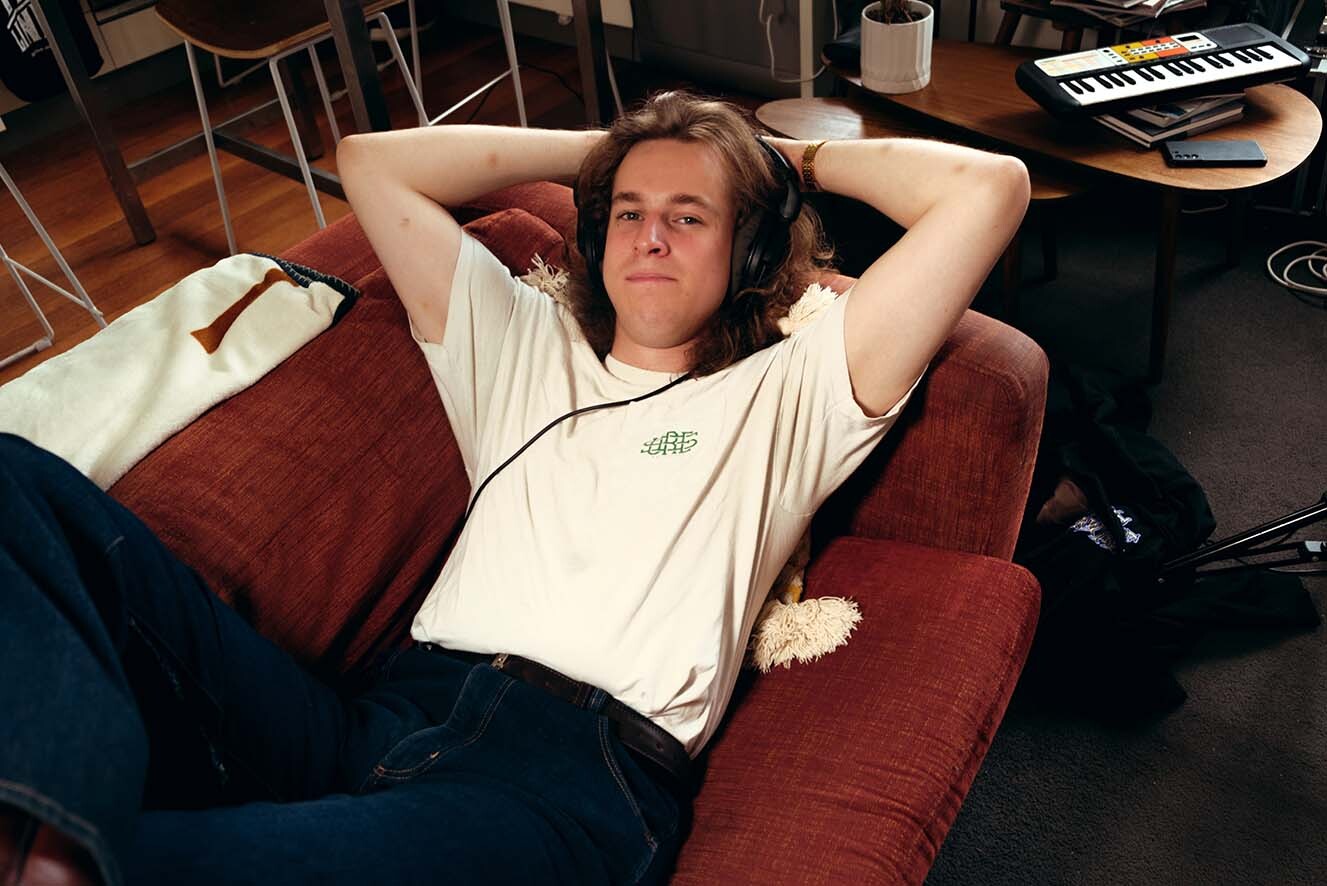 A young man laying on a couch with headphones on. A young man laying on a couch with headphones on.