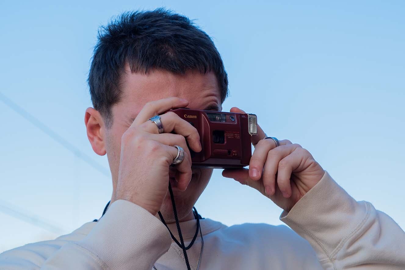 A young man taking a film photo. A young man taking a film photo.