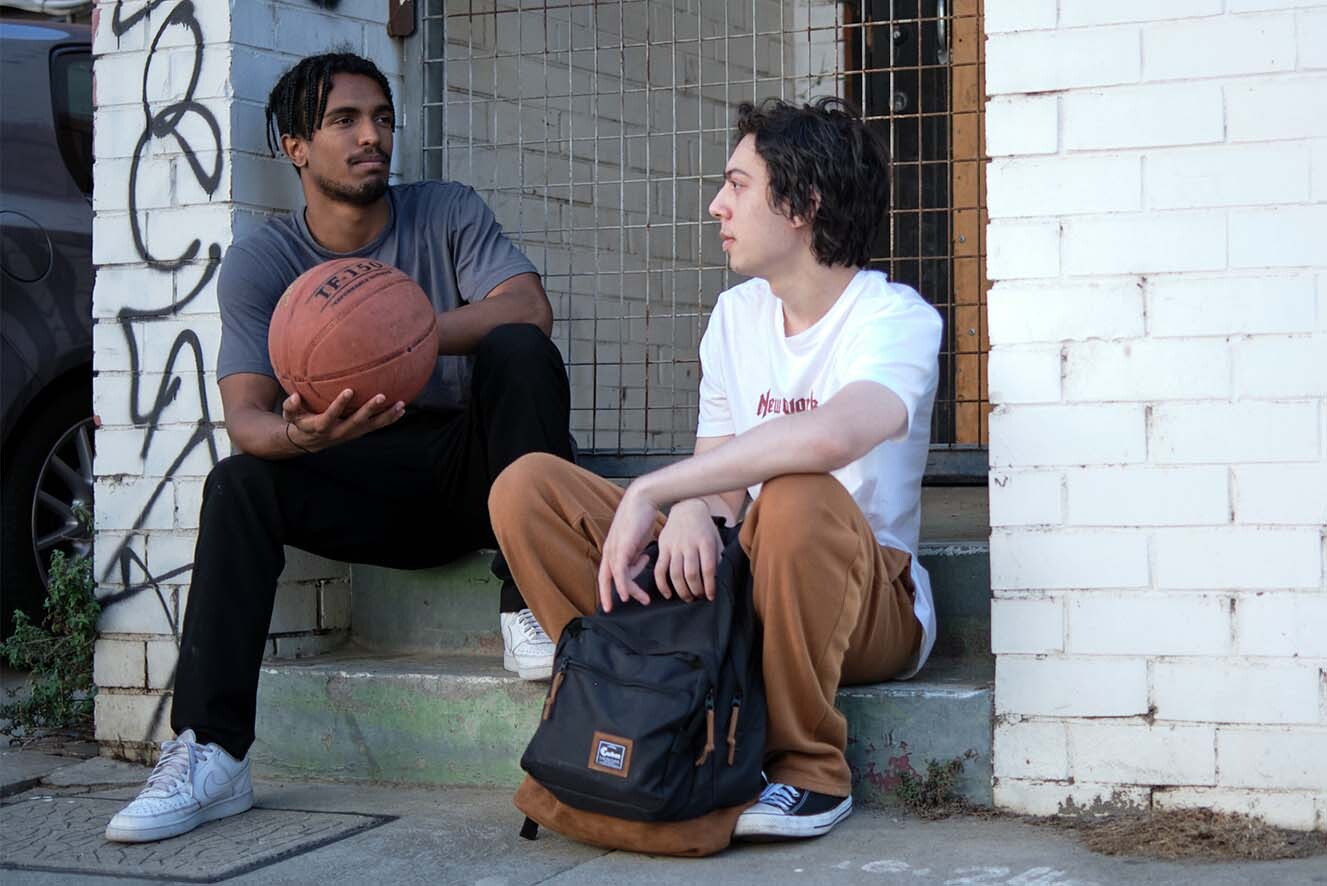 Two young men sitting on a step on the street.