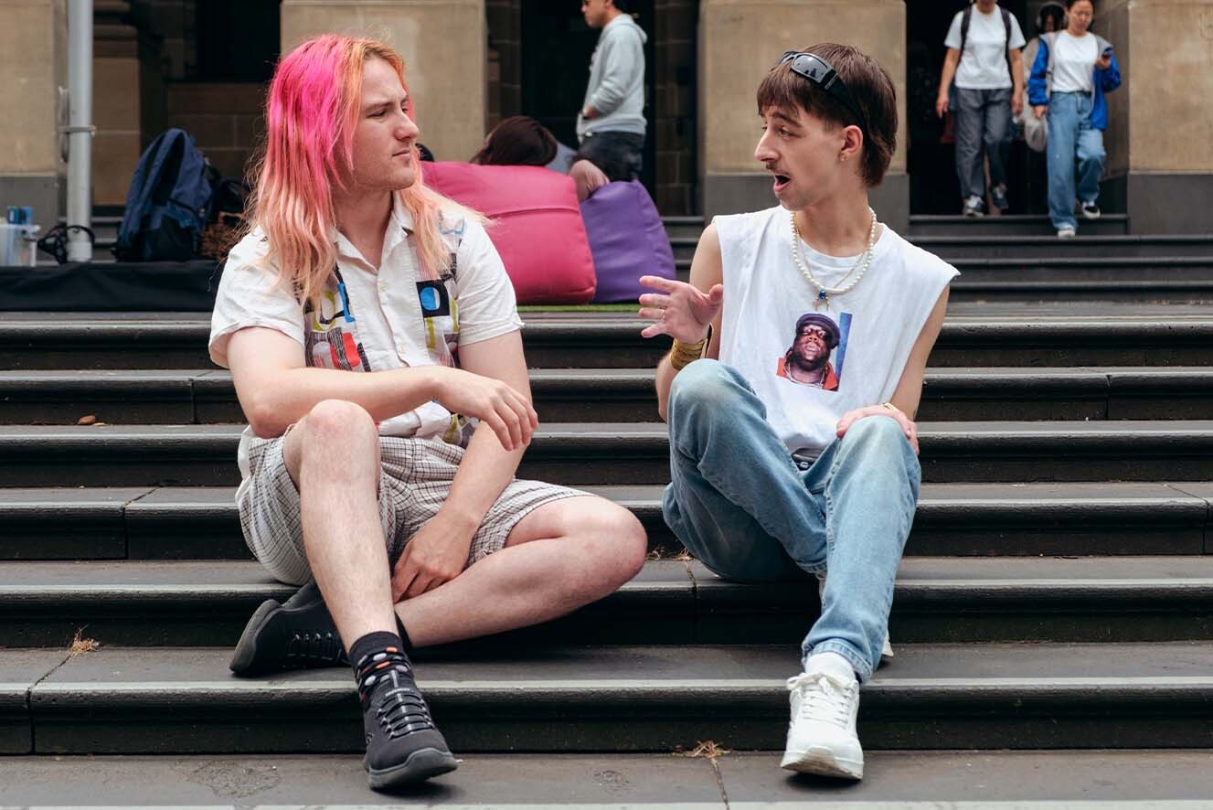 Two young people sitting on a step while in conversation. Two young people sitting on a step while in conversation.